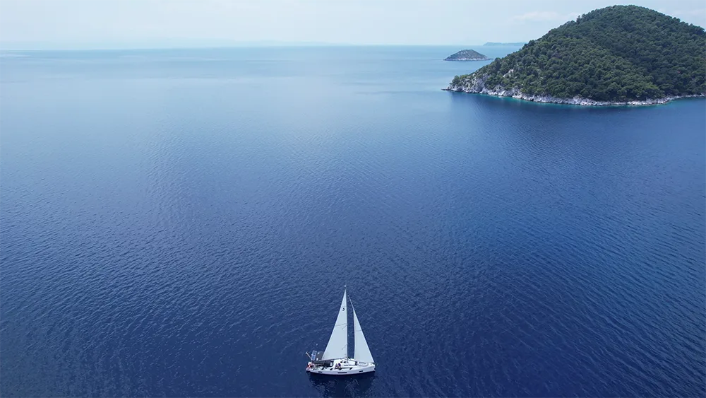 Sailing yacht in the National Marine Park of Alonnisos, near a small pine-covered islet.