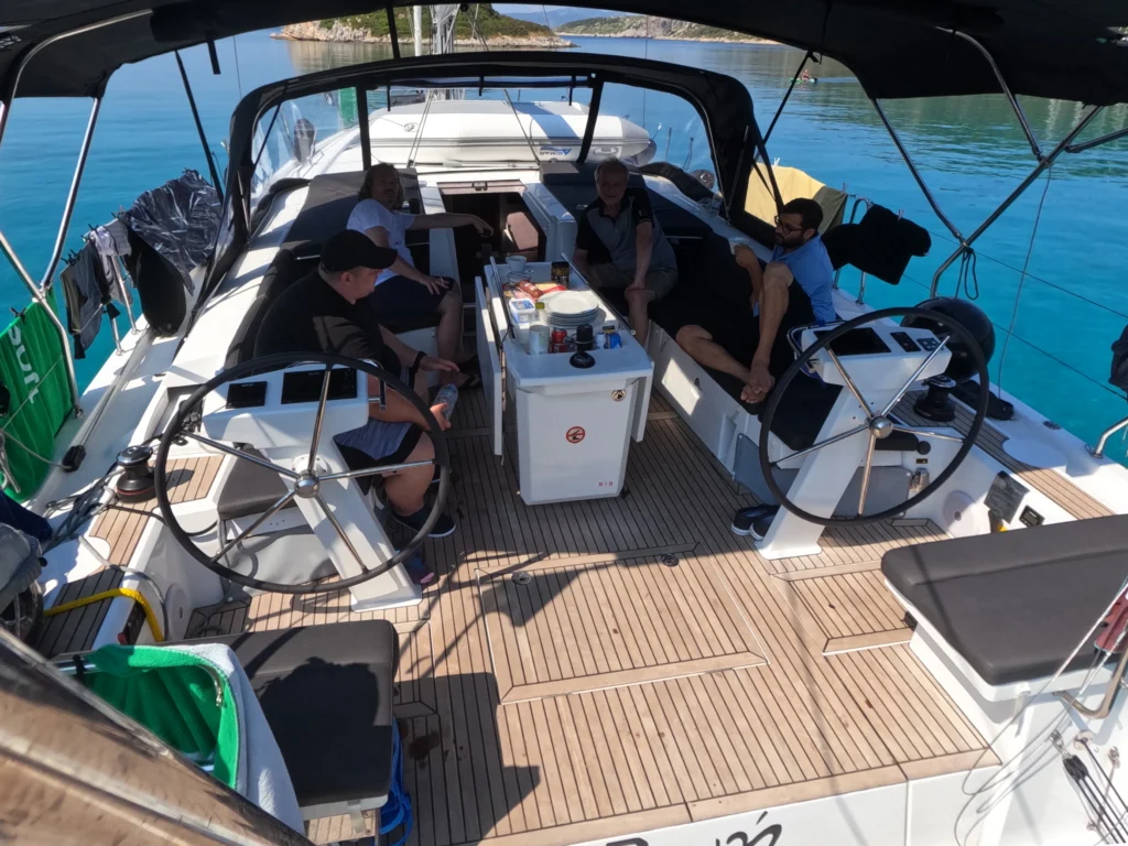 Spacious cockpit of sailing yacht Zoe with guests relaxing comfortably at anchor